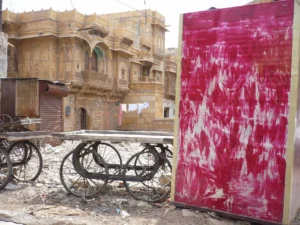 Scène d’architecture urbaine en Inde avec une façade traditionnelle en pierre jaune et un panneau rouge texturé, photographiée dans un style documentaire.