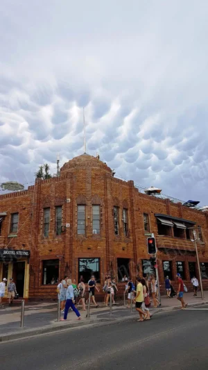Bâtiment en briques de Manly à Sydney sous un ciel mamelonné spectaculaire, scène urbaine avec passants.