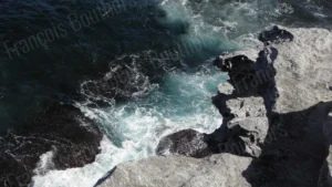 Vue plongeante sur une falaise rocheuse et l’eau turquoise agitée — Photographie de paysage marin par François Bouthors