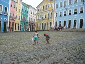 Maisons coloniales colorées du Pelourinho à Salvador de Bahia, avec deux enfants jouant sur une place pavée — Photographie d’architecture urbaine.
