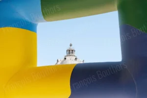 Photographie d’architecture montrant un dôme encadré par des structures colorées sur fond de ciel bleu