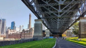 Vue sous le Sydney Harbour Bridge avec sa structure métallique et la skyline de Sydney en arrière-plan