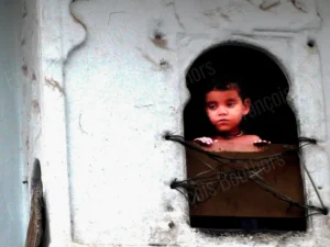 Photographie portrait d’un enfant regardant par une fenêtre en Inde par François Bouthors.