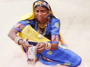 Photographie de portrait d’une femme en tenue traditionnelle tenant des bijoux argentés, par François Bouthors.