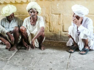 Photographie portrait de trois hommes aux turbans blancs assis contre un mur en Inde – François Bouthors