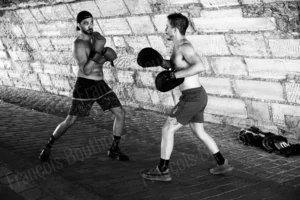 Photographie urbaine en noir et blanc de deux hommes s’entraînant à la boxe sous un pont – François Bouthors