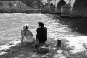 Street photo d’un couple assis au bord de l’eau dans une scène urbaine en noir et blanc – François Bouthors